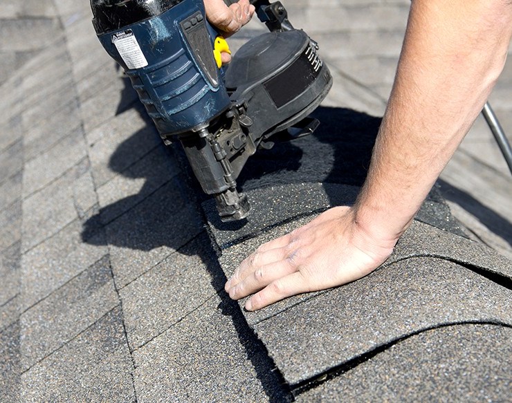 Roofer repairing asphalt shingles